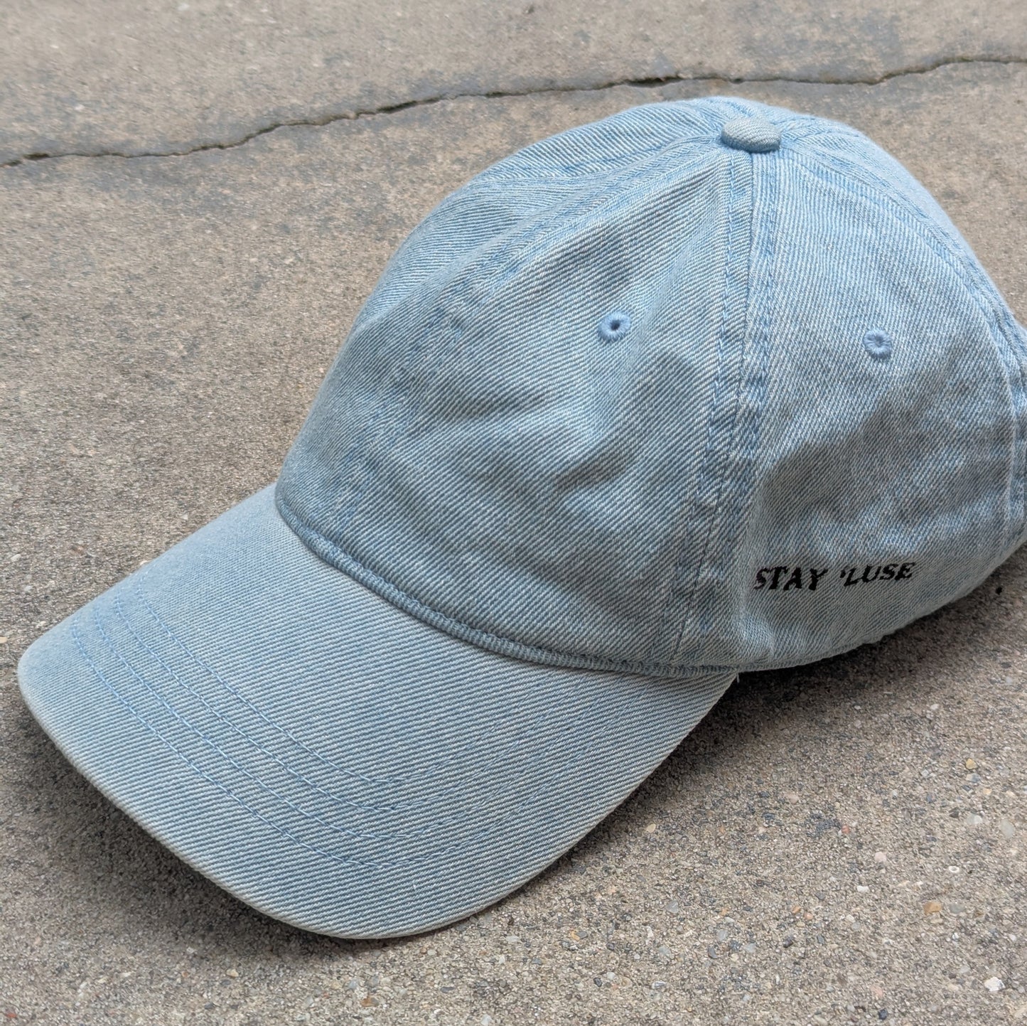 Stay 'luse denim hat in light blue. Stay 'luse embroidered on left side.