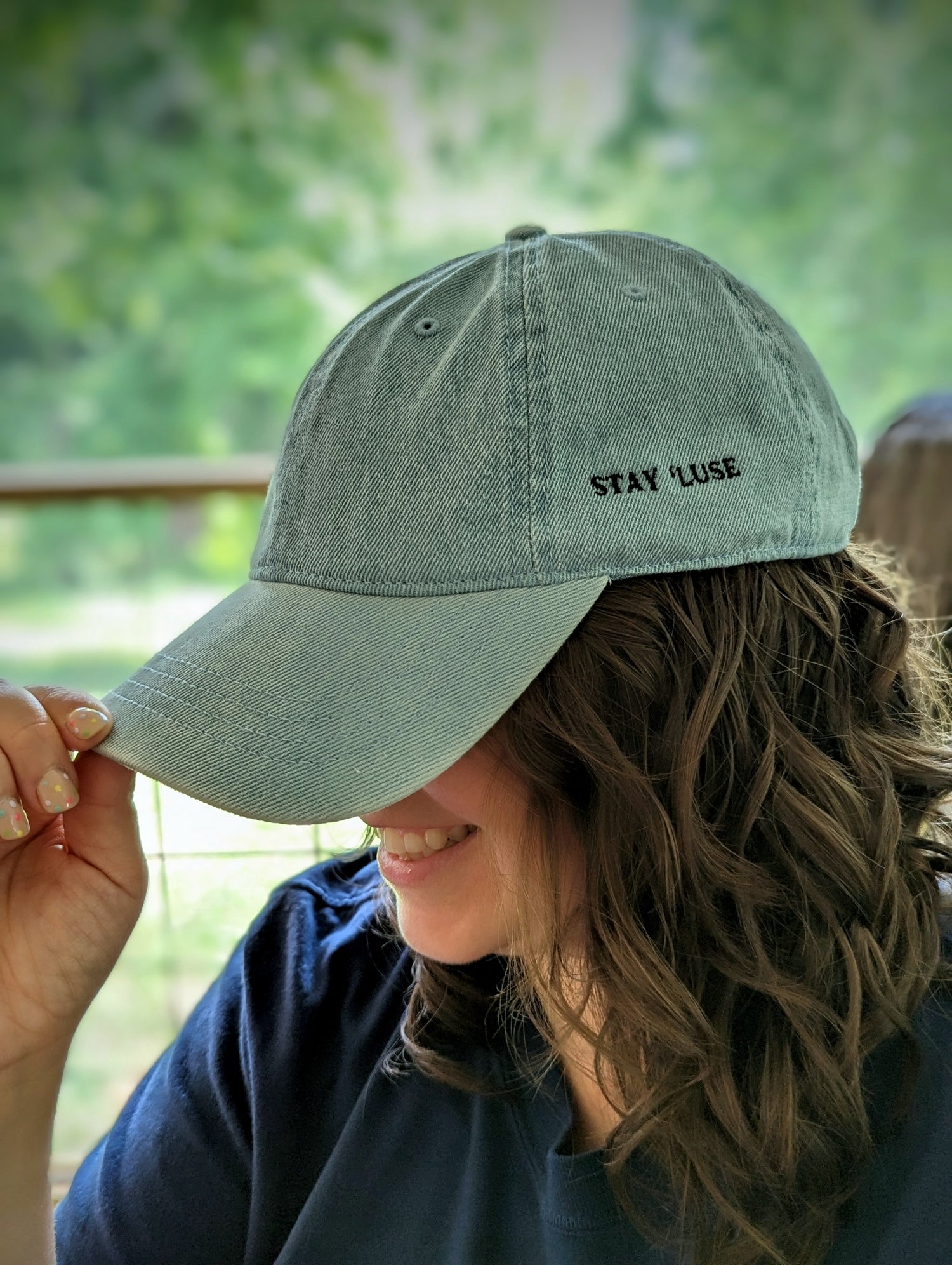 Woman smiling while wearing light blue Stay 'luse denim hat.
