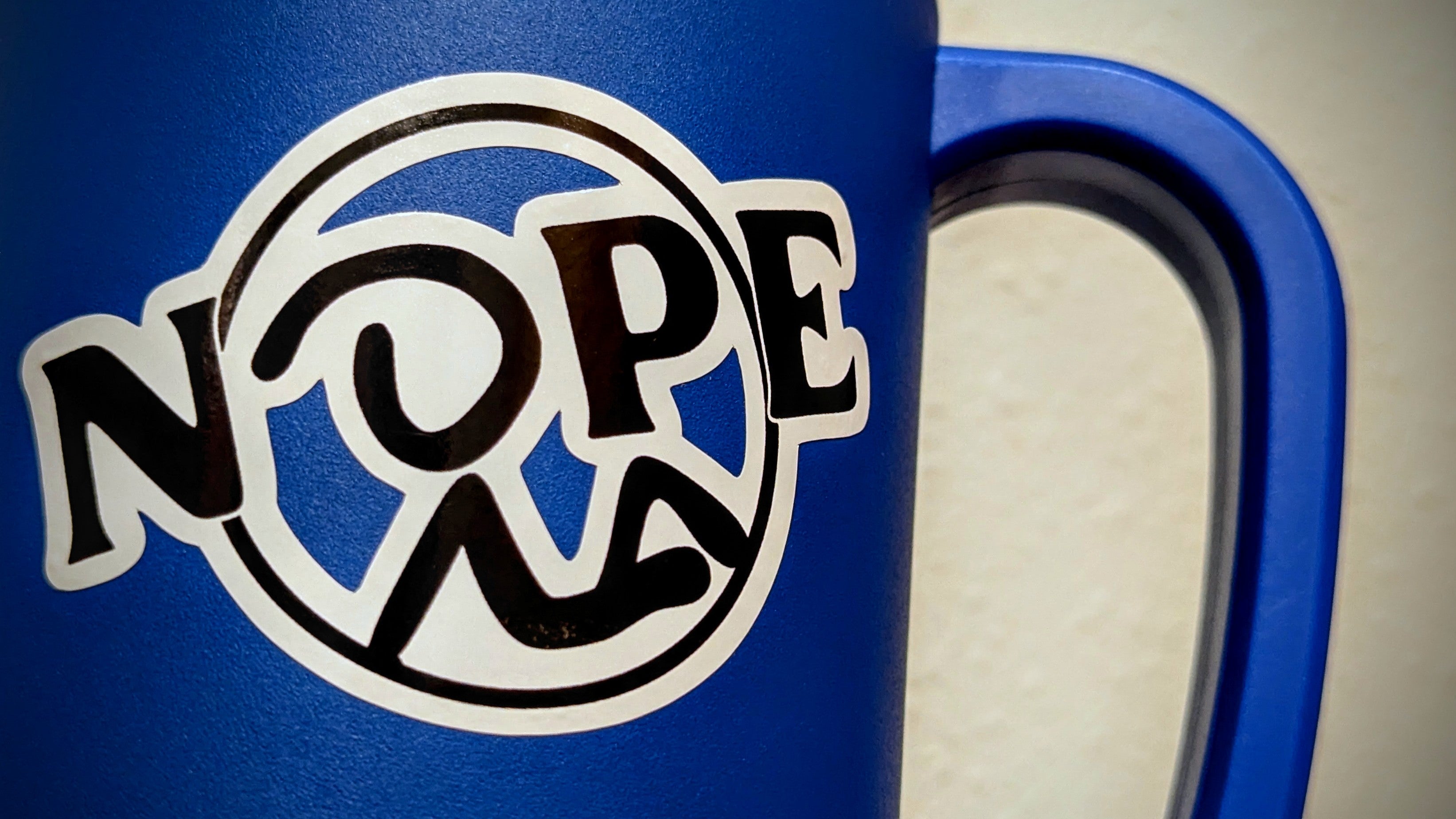 Black and white Nope sticker shown stuck to large blue cup.