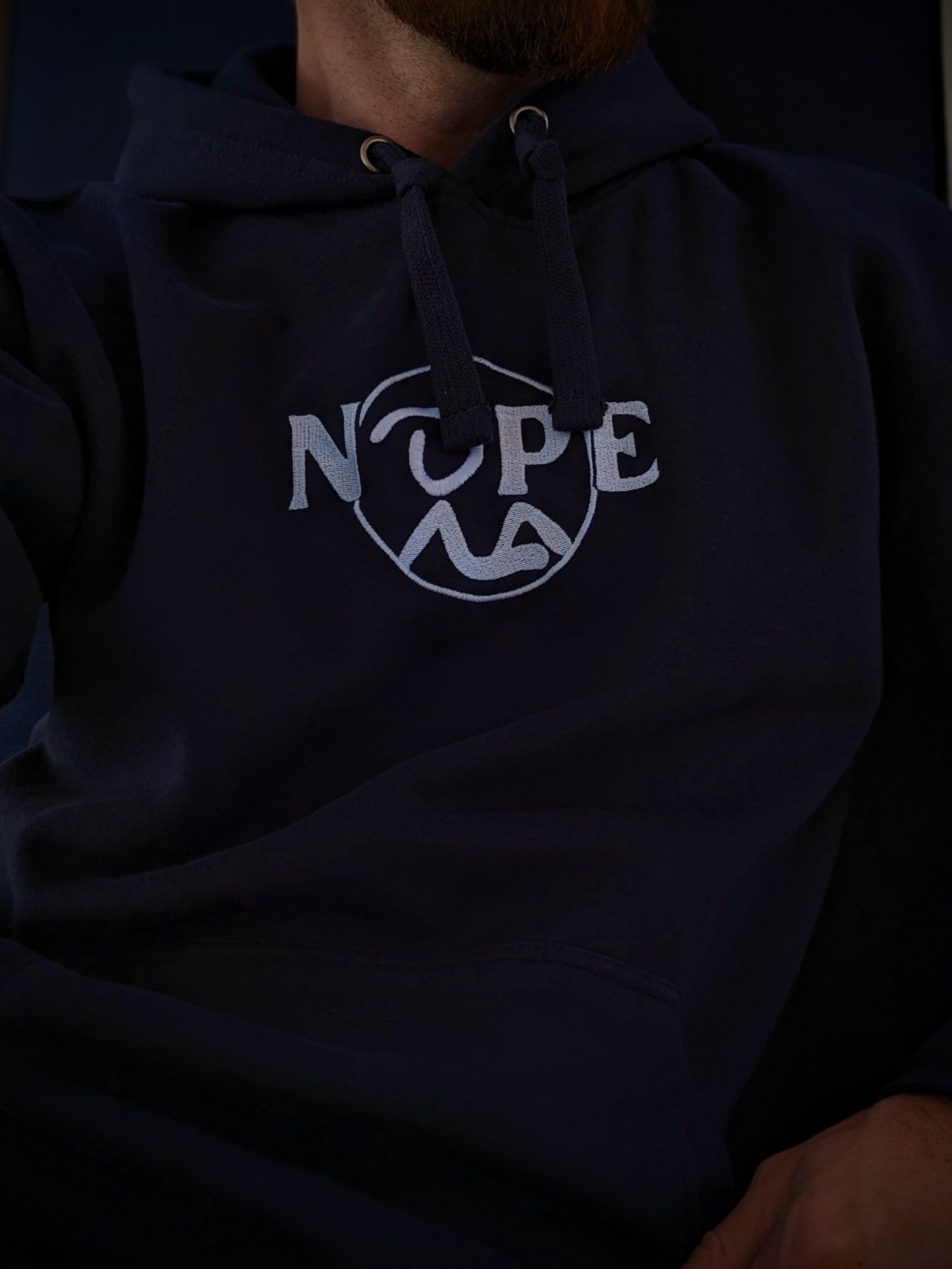 Torso of Man sitting in Navy Nope Hoodie.