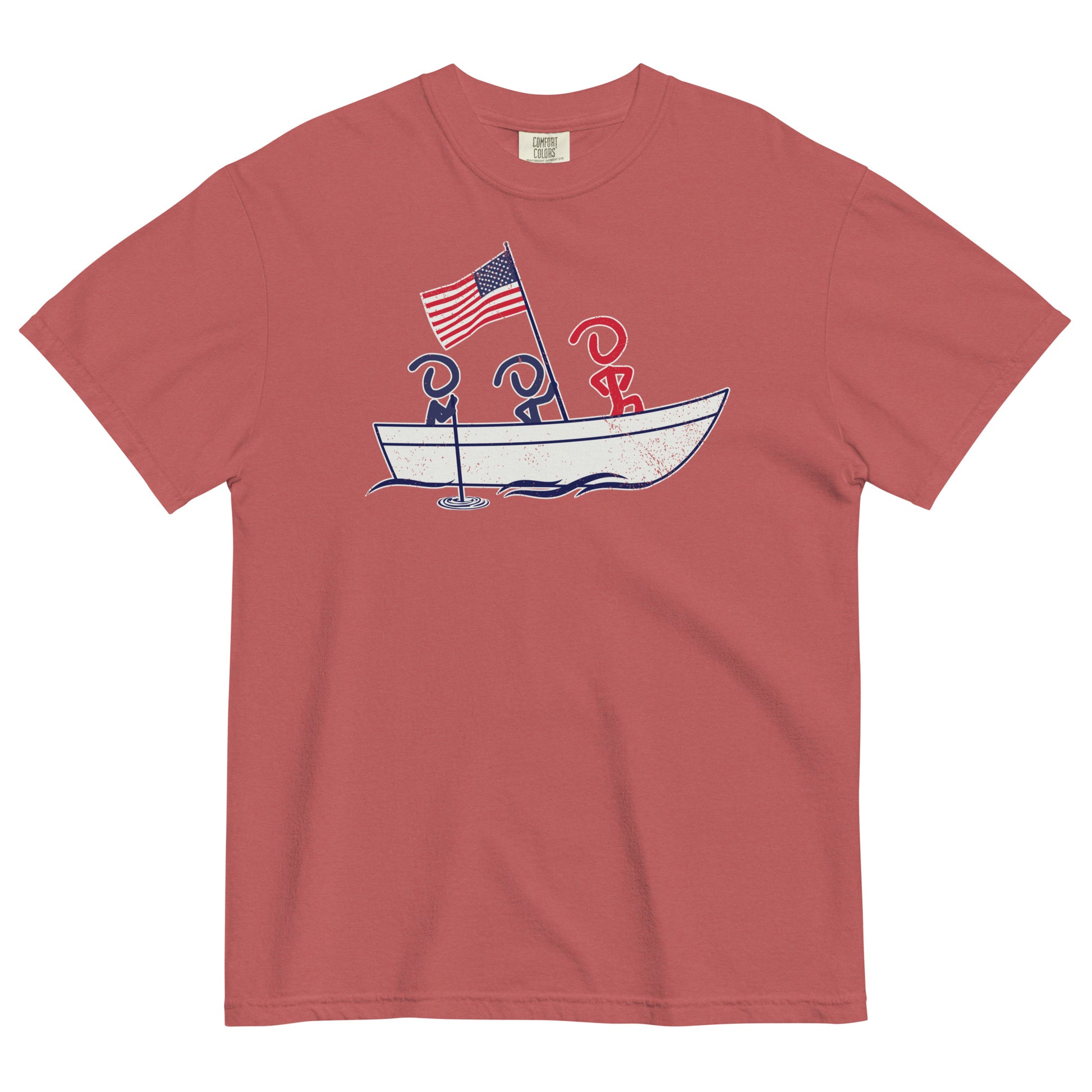 A red short sleeve t-shirt laid flat. Front graphic shows three Jaunty Men in a simple boat carrying an American flag, similar to George Washington crossing the Delaware.