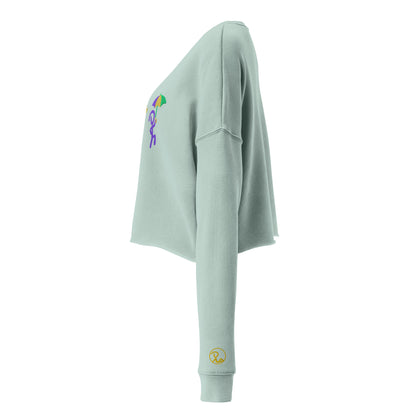 Left side view of dusty blue cropped sweater with 3 "Jaunty Man" stick figures embroidered in gold, green, and purple, and holding a drink, a trumpet, and an umbrella, respectively. Recluse Rags logo without text on left wrist.